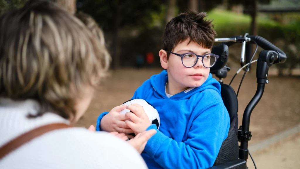 Young boy in a wheelchair holding a small ball