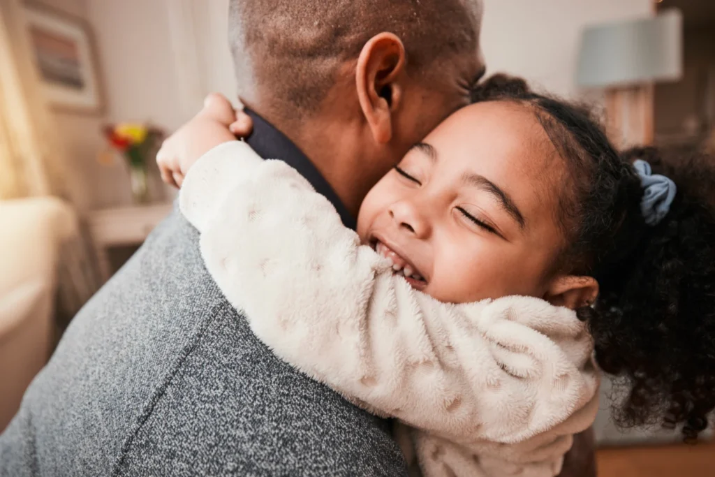 Young girl hugging a male parent figure