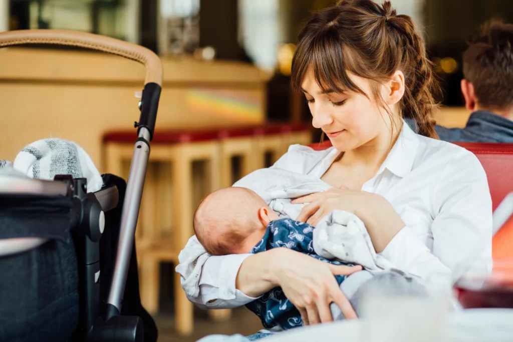 A young mother is breastfeeding her baby in a cafe